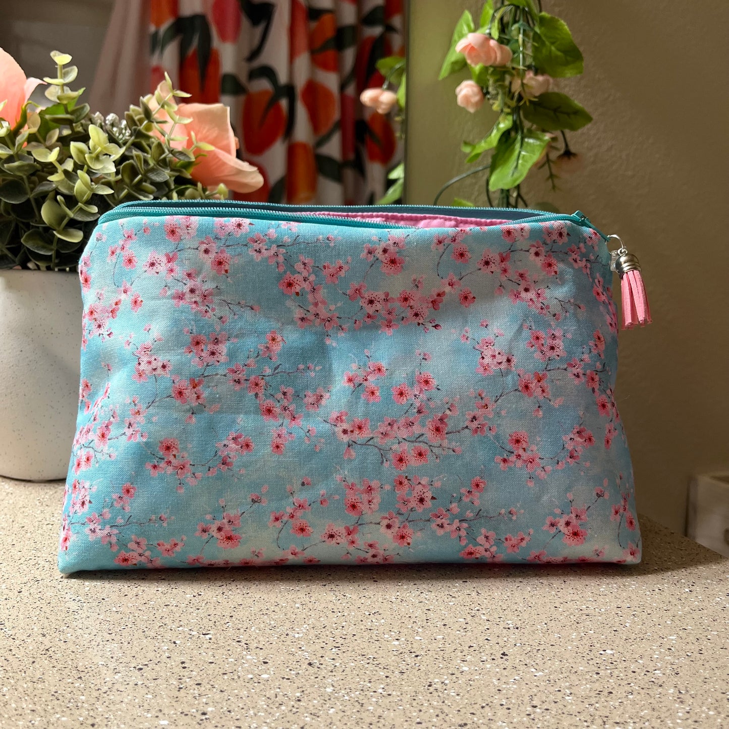 Floral-patterned pouch on a textured surface with plants in the background
