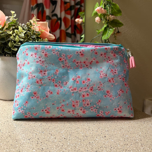 Floral-patterned pouch on a textured surface with plants in the background